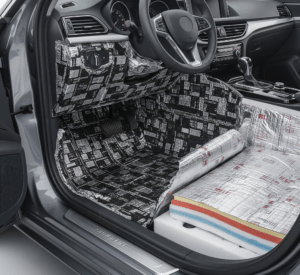 Tampilan interior mobil dari sisi pengemudi dengan lantai dan panel bawah pintu terbuka, menunjukkan lapisan peredam mobil akustik dan insulasi termal.