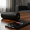 Speaker Bluetooth hitam modern di samping ponsel dengan baterai lemah, menggambarkan frustrasi akan kenapa baterai speaker bluetooth cepat habis.