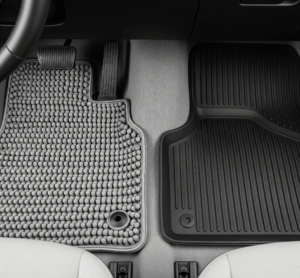 Tampilan atas lantai mobil yang menunjukkan perbedaan tekstur antara karpet PVC abu-abu bertekstur bulat dan karpet karet hitam bertekstur bergaris, sebagai perbandingan karpet pvc vs karet.